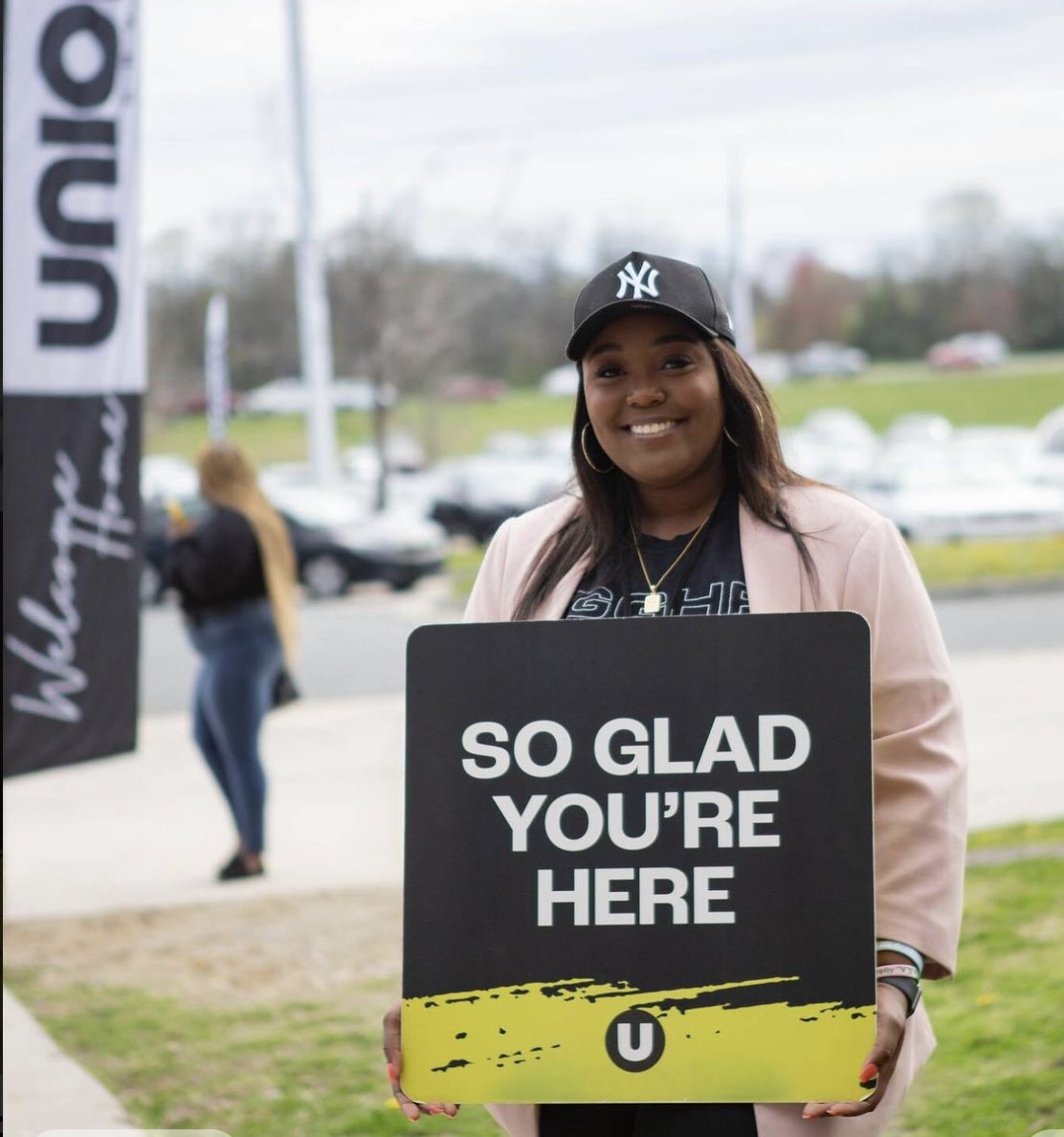 Welcome team holding So Glad You're Here church welcome signs